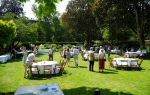 Alumni and guests in the President's Garden with tables set up with white tablecloths and wooden chairs.