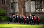 A group of people processing from Cloister Court to the Chapel wearing their gowns