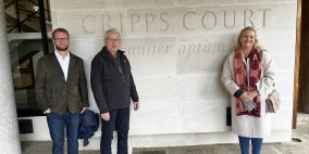 Three people standing in front of the Cripps Court inscription